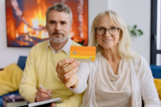 an elderly woman holding a sim card beside an elderly man